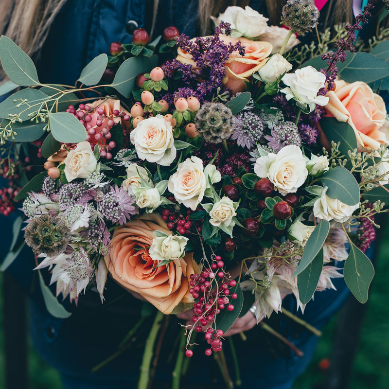 Hand-tied bouquet of peach and cream roses with berries and eucalyptus
